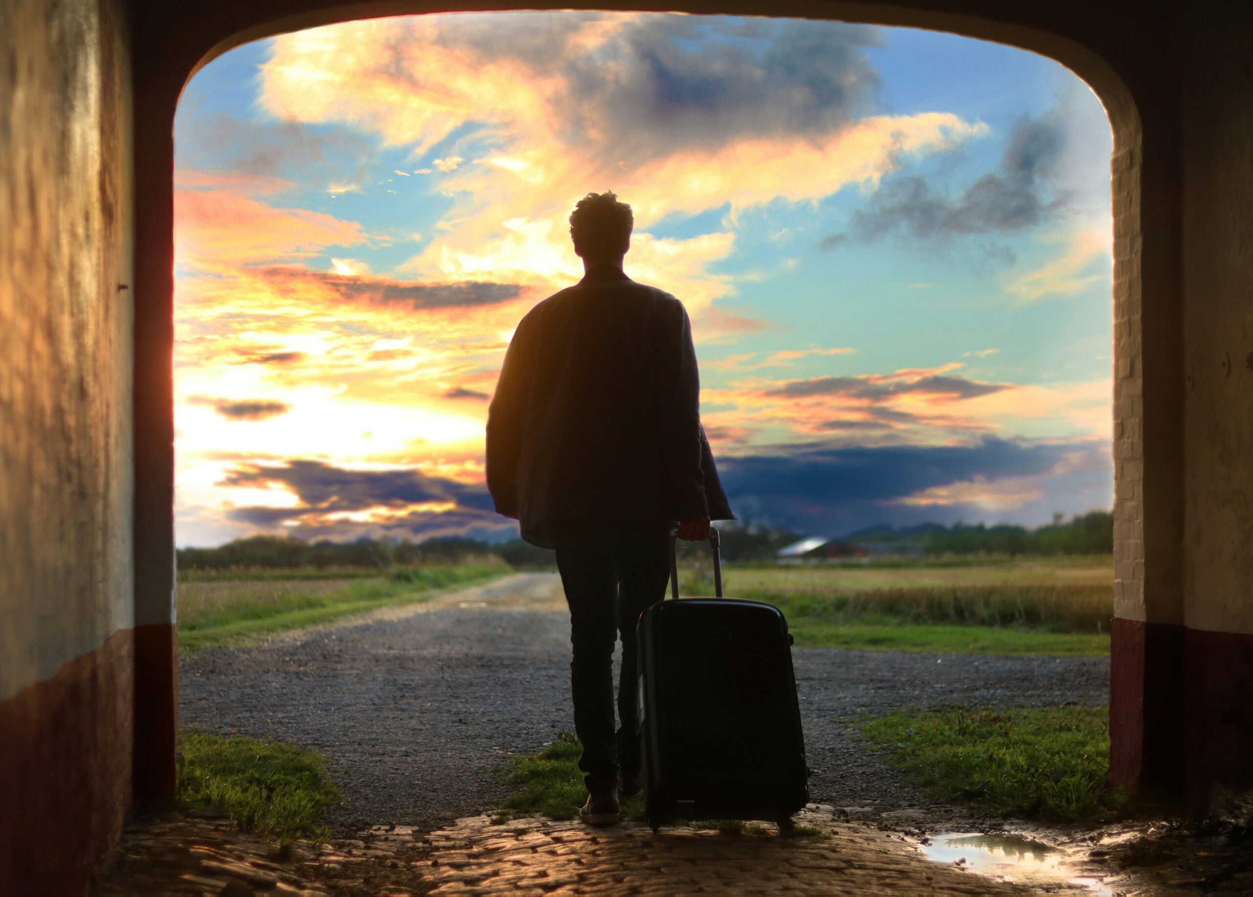 Packing list Traveler walking toward the sunset with a rolling suitcase, ready for the next trip